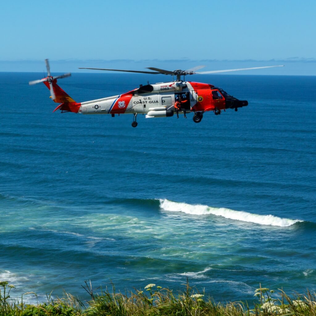A Coast Guard helicopter flying over the blue ocean on a clear day.