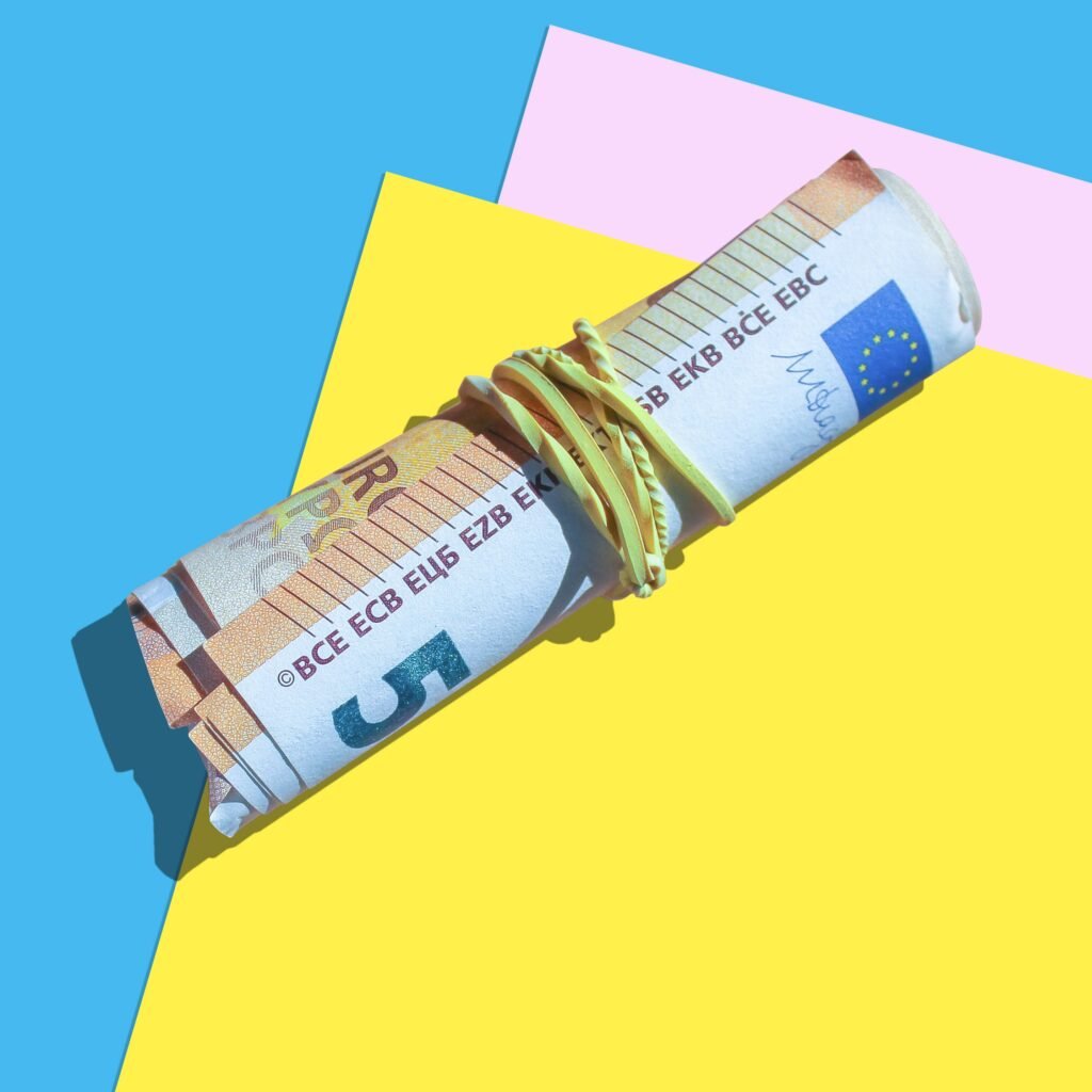 High angle shot of rolled euro notes with rubber band on vibrant surfaces.